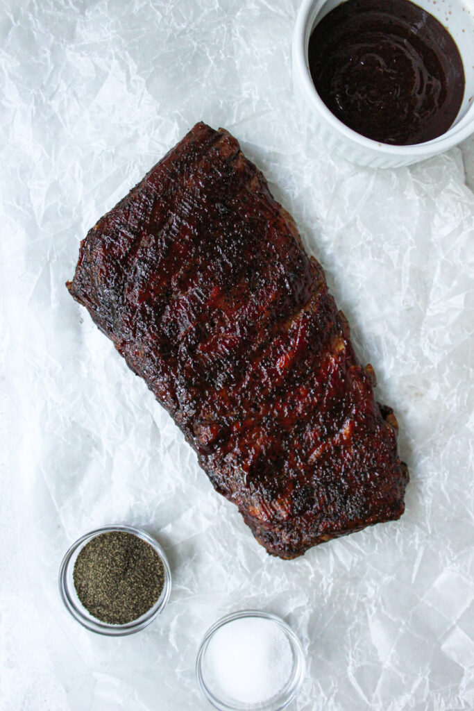 Top view of St. Louis Smoked Ribs! Salt, pepper, and BBQ sauce are show in the picture.